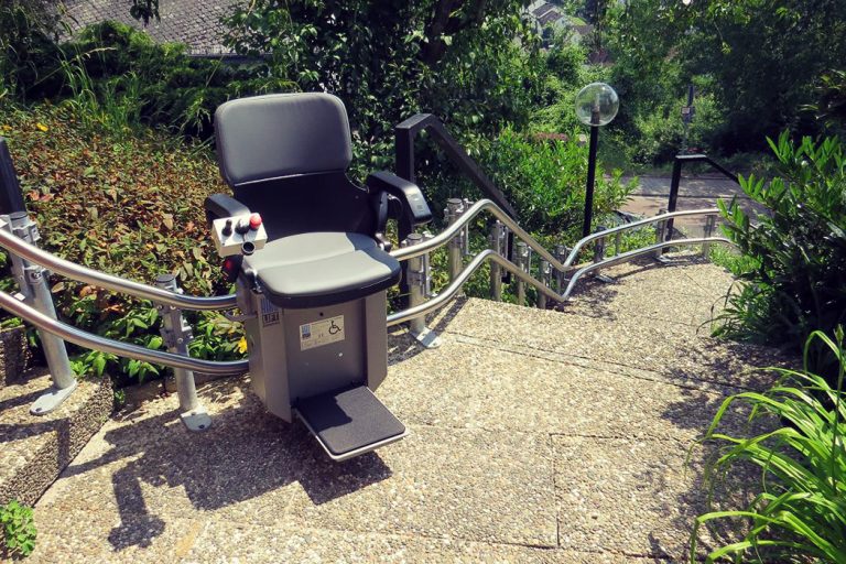 Treppenlift an einer langen Außentreppe im Sommer