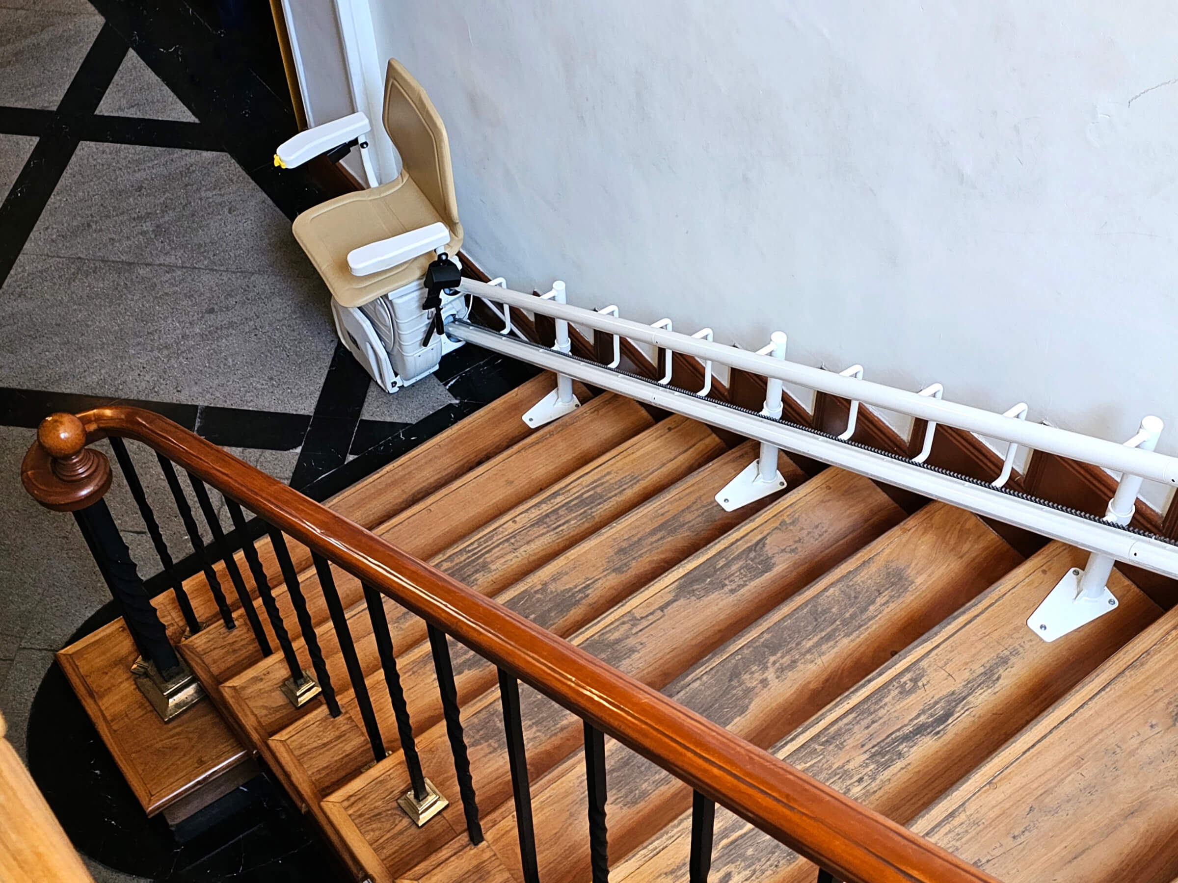 Treppenlift auf einer Holztreppe, der für barrierefreies Wohnen sorgt, mit stabiler Schiene und Sitzplatz für sicheren Transport zwischen den Etagen.